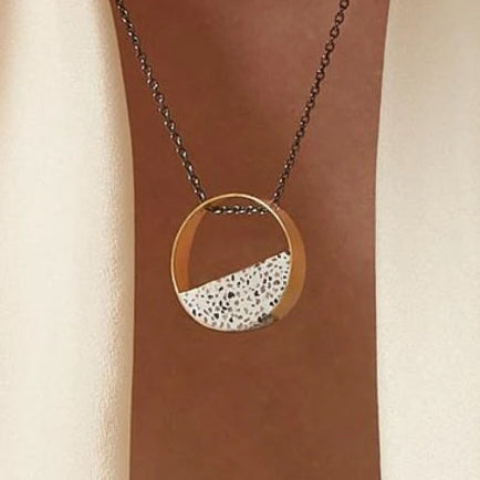 Close-up of a gold-plated pendant necklace featuring a handcrafted terrazzo inlay suspended from a delicate chain.